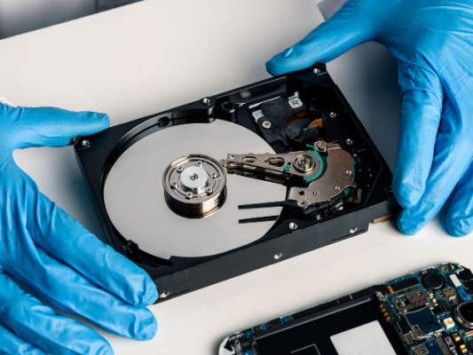 A technician servicing an opened hard disk drive